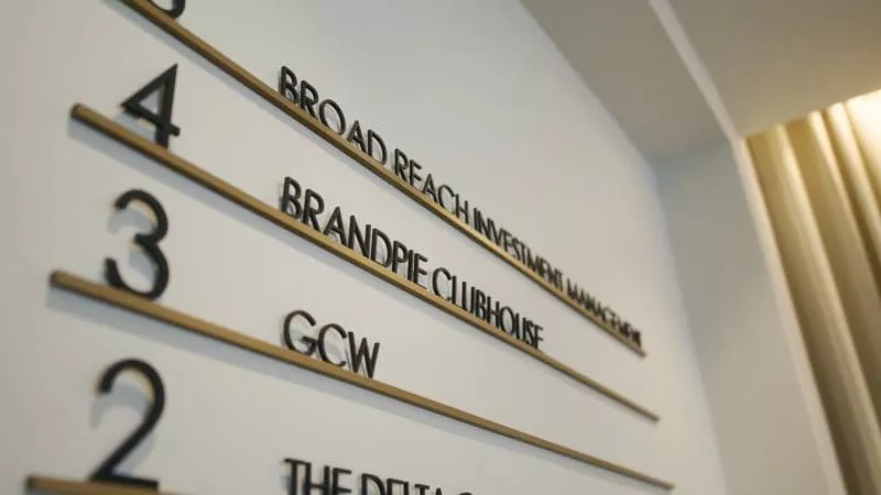 Close-up of an office wall directory showing floor numbers and company names, including “Brandpie Clubhouse”.