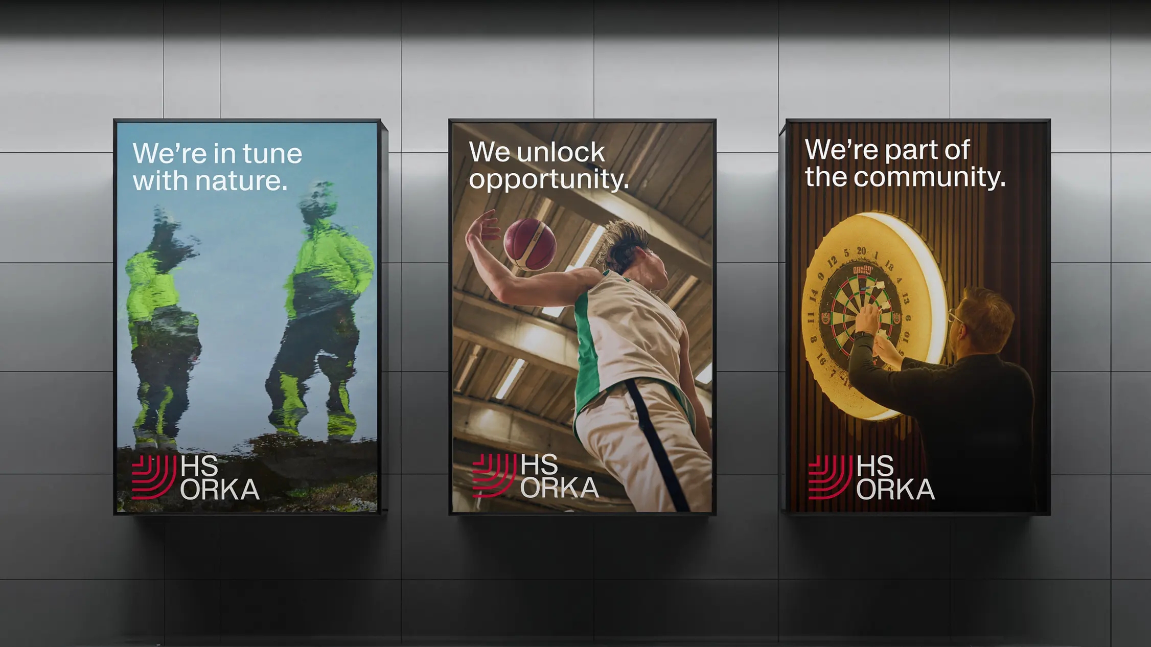 Three large vertical brand posters displayed side by side on a wall promoting HS Orka’s “Respectful Innovation” identity. The left poster shows two workers in reflective gear standing in nature with the text “We’re in tune with nature.” The center poster features a person playing basketball reaching up with a ball, with the text “We unlock opportunity.” The right poster shows someone aiming at a dartboard in a social setting with the words “We’re part of the community.” Each poster includes the red and white HS Orka logo at the bottom