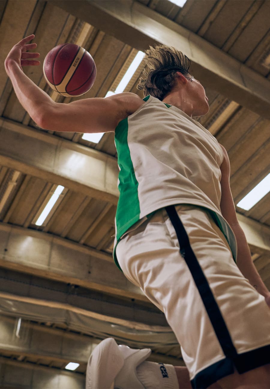 A candid editorial-style photograph showing a group of Icelandic workers and community members engaged around HS Orka’s geothermal site. The scene includes people in workwear interacting with natural and industrial elements—such as rugged lava rock landscapes, steam vents, power plant structures, and geothermal equipment—capturing dramatic Icelandic light and weather conditions to reflect the human side of the energy company’s operations. This photography style is part of HS Orka’s brand work emphasizing real people and place within its renewable energy story.